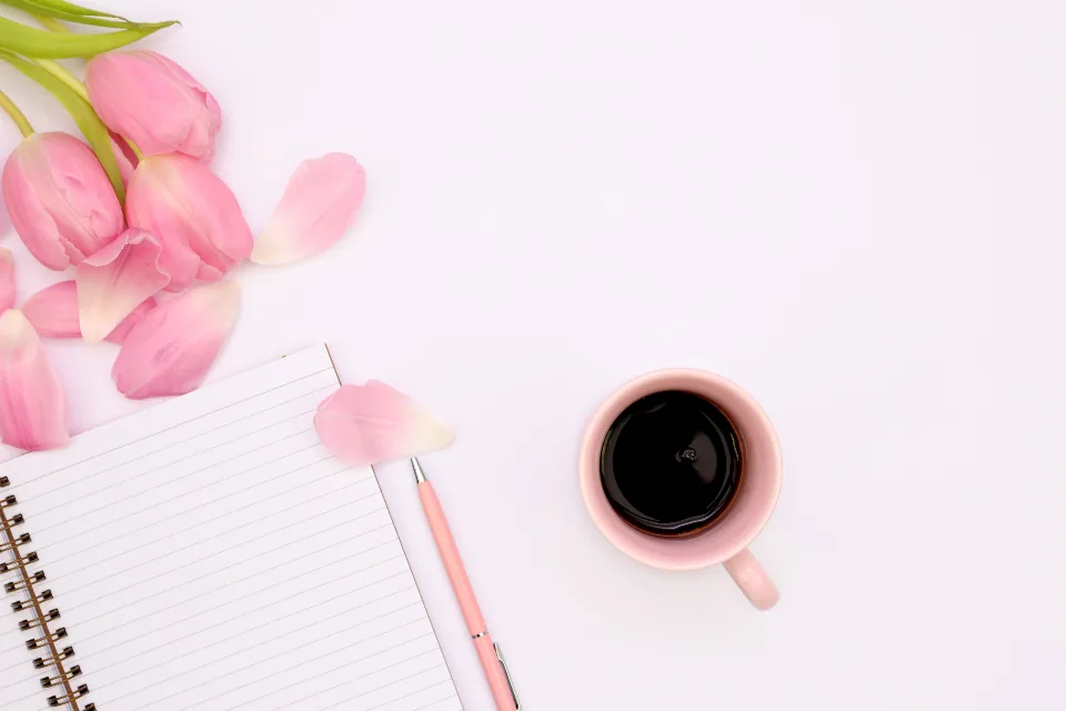 An open notebook with a pink pen, pink tulips and a cup of coffee, ready for a 369 method session