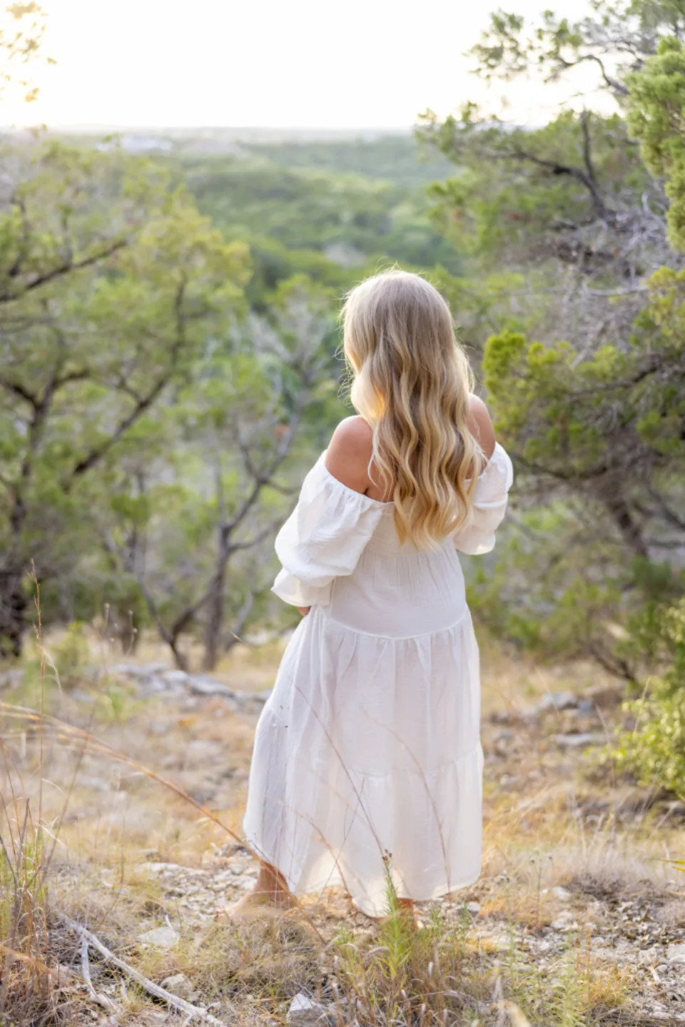 A woman in a white dress walking into golden evening light