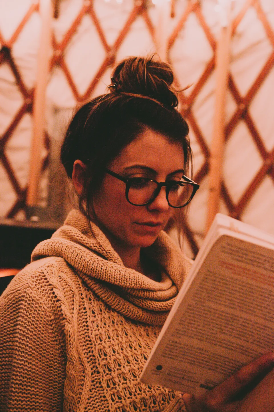 A woman in glasses reading closely, checking whether manifestation works according to the research