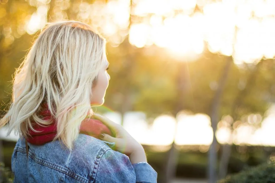 A woman with blonde hair looking out into golden evening light, reflecting on whether manifesting is real