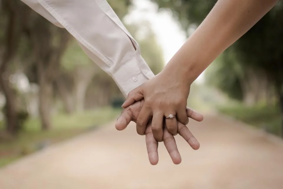 Two people holding hands on a tree-lined path, a hopeful image for manifesting a specific person