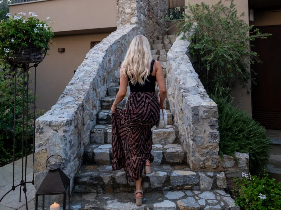 A woman walking up old stone stairs, one step at a time, like learning to manifest when you don't believe yet