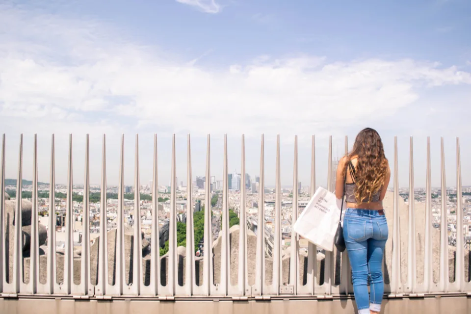 A woman standing on a rooftop terrace looking out over a city, open to what's possible